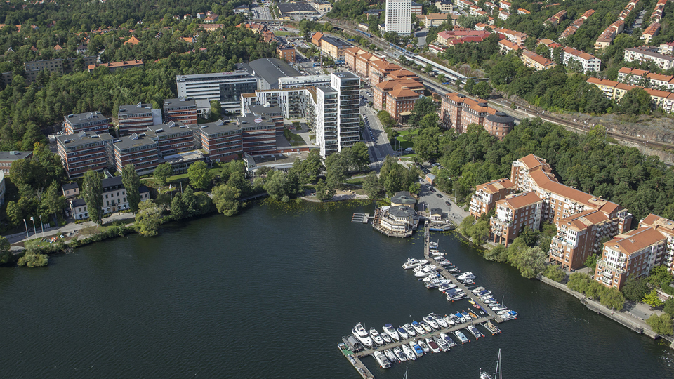 Flygfoto över Tranebergs strand med kontorshus, bostadshus och båtar vid båtklubb.